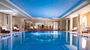 A large indoor swimming pool with a starry ceiling, lounge chairs, and a view of the outdoors. - Park Hotel Ville Montefiori (Gardone Riviera)