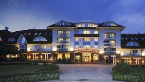 A large, multi-story hotel with a central entrance, multiple balconies, and a well-lit facade. - MenDan Magic Spa & Wellness Hotel (Zalakaros)