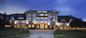 A large, multi-story hotel with a central entrance, balconies, and a well-lit facade.