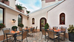 An outdoor patio with stone flooring, wicker chairs, and tables set for dining. - Altdeutsche Weinstube (Ruedesheim am Rhein)