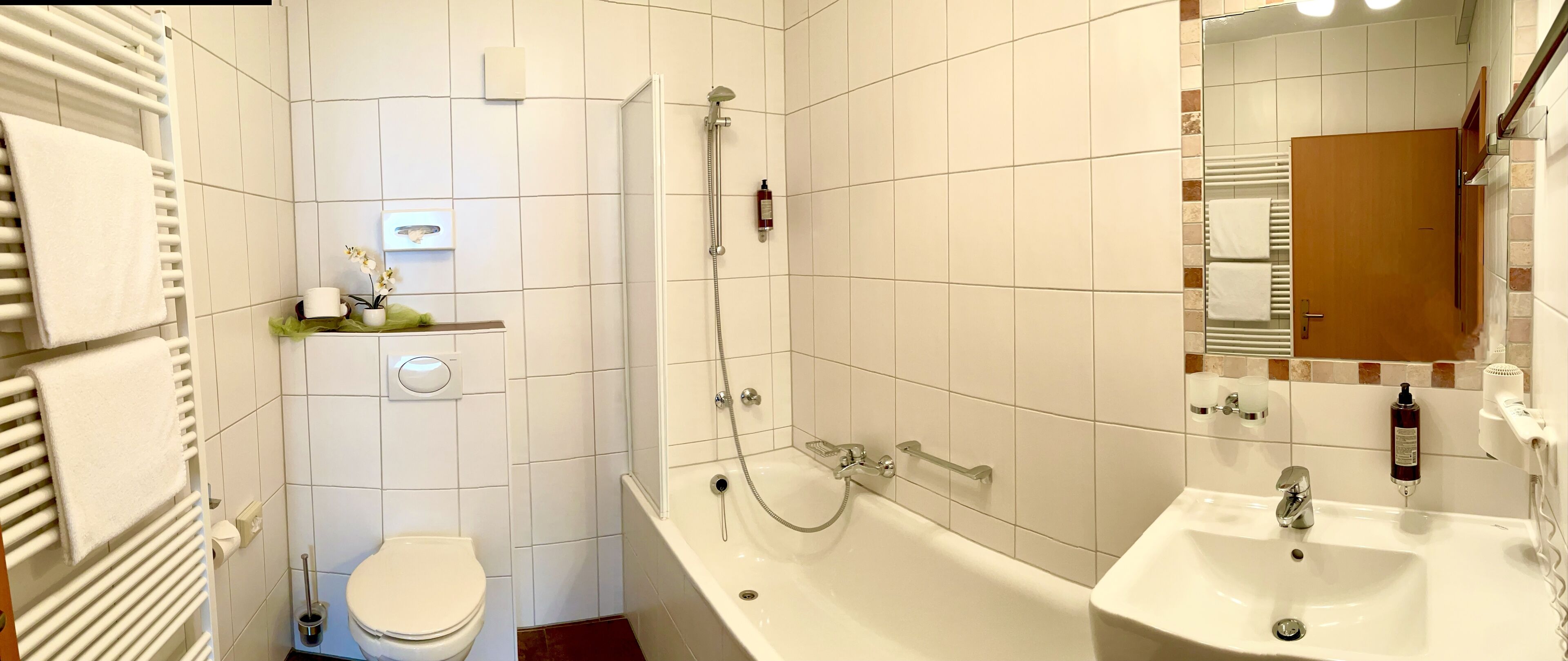 A bathroom with a toilet, bathtub, and two sinks.