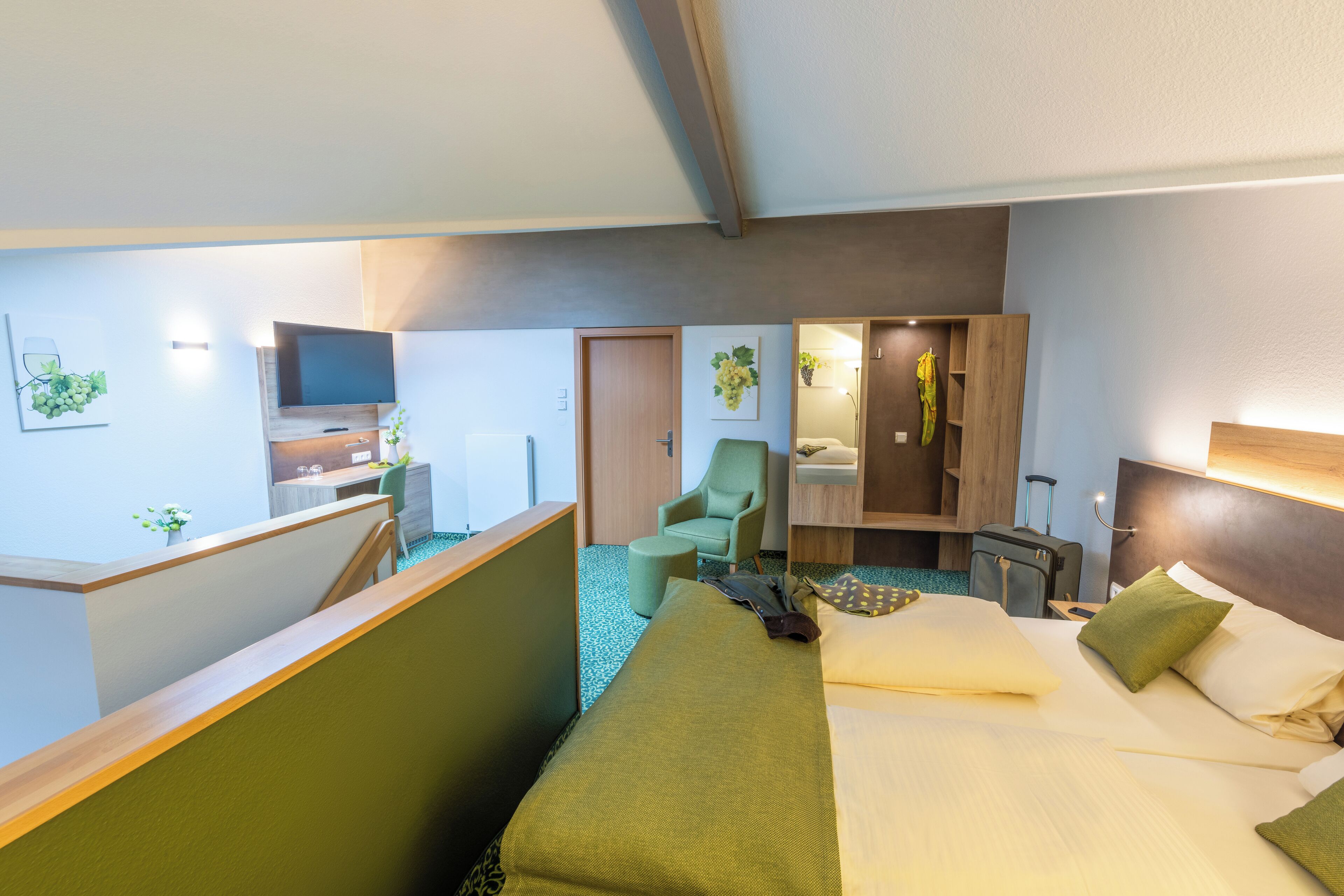 A hotel room with a bed, a desk, a chair, a mirror, and a small table.