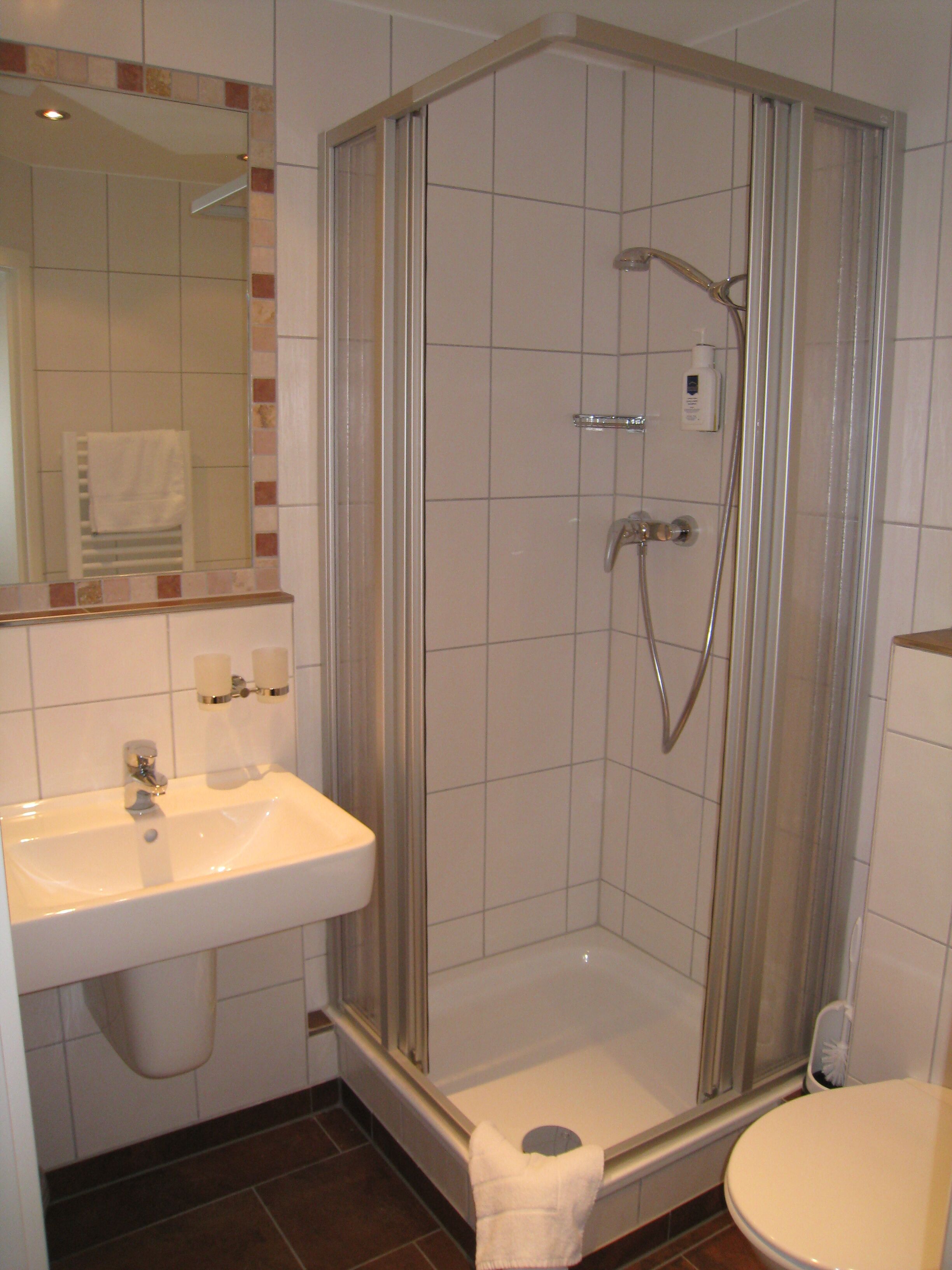 Ein Badezimmer mit einer Duschkabine, einem Waschbecken und einer Toilette.