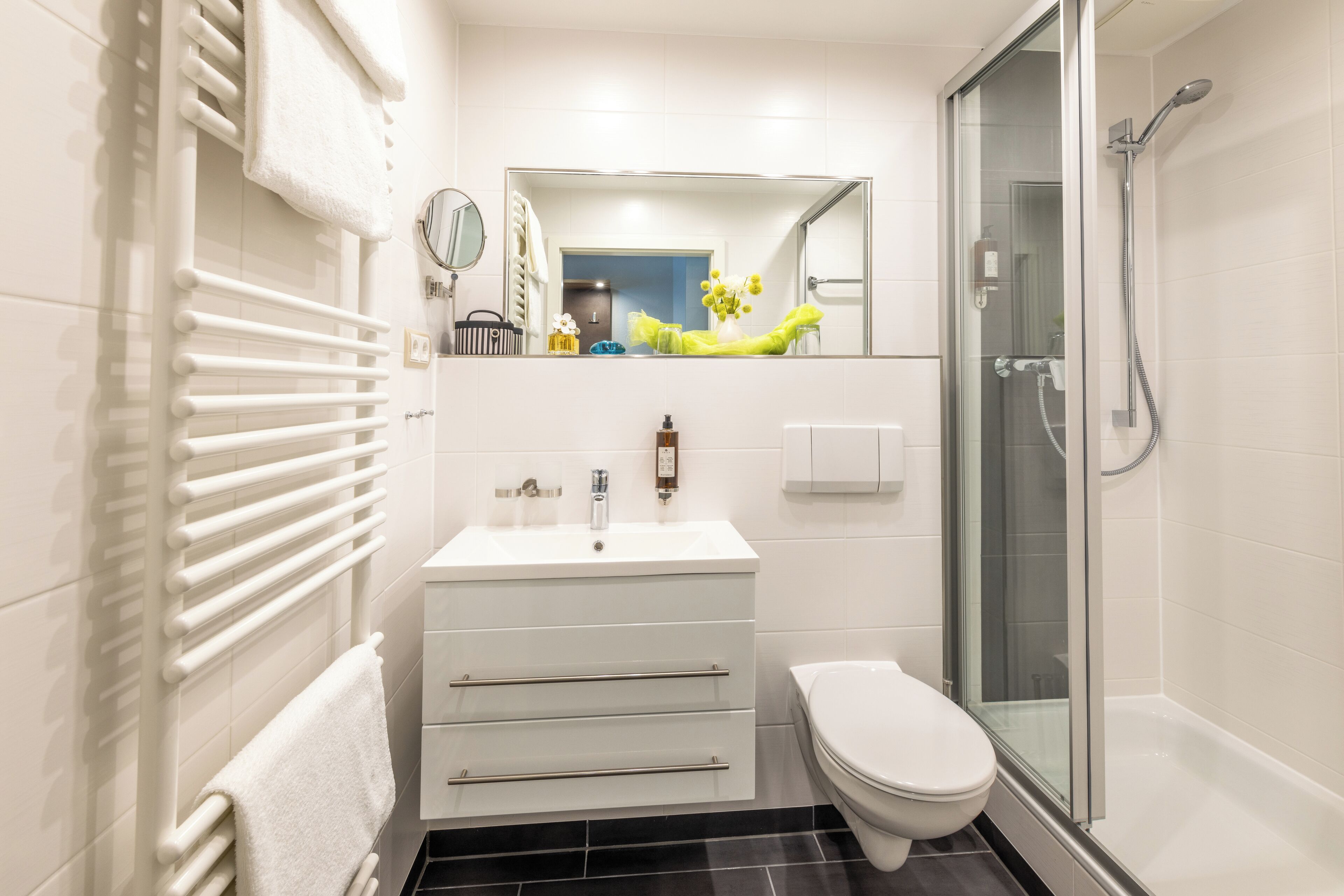 A modern bathroom with a white sink, toilet, and glass shower enclosure.