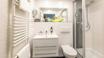 Une salle de bain moderne avec un lavabo blanc, des toilettes et une douche à parois de verre.