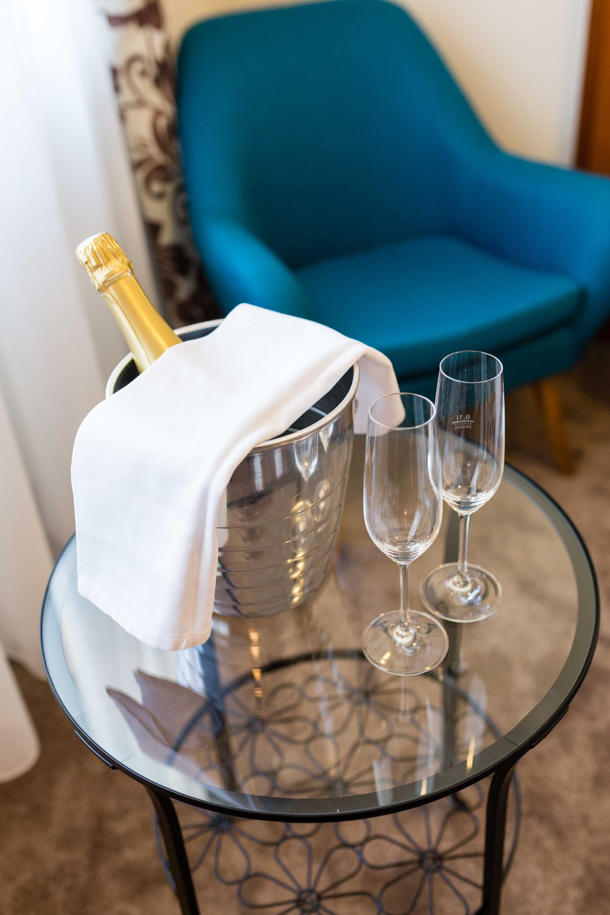 A glass table with a champagne bottle and two glasses.