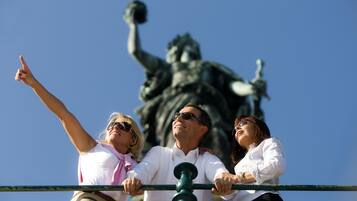 A group of people standing in front of a statue, with a clear blue sky in the background.