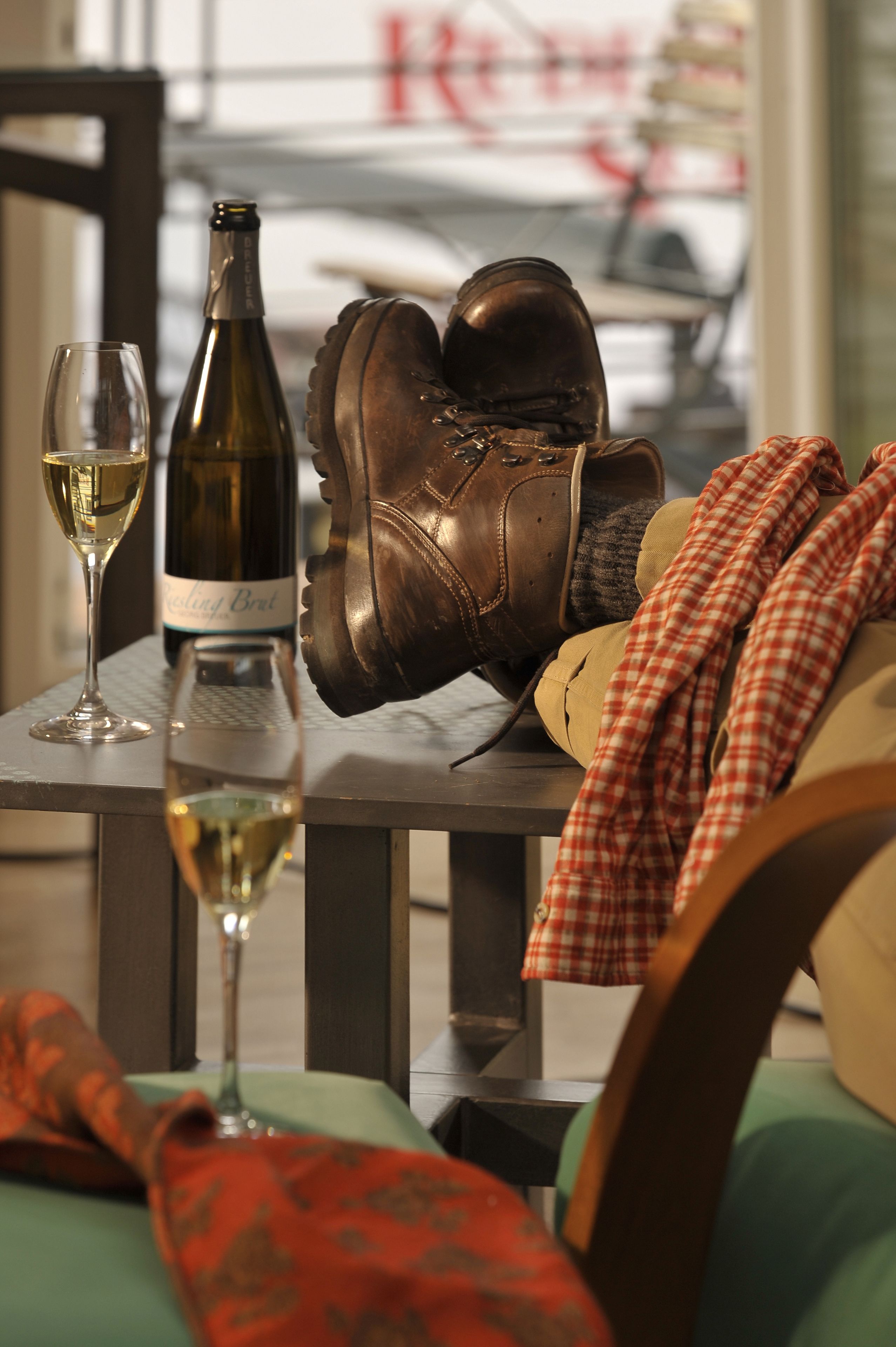 A table with a wine bottle, glasses, and a pair of boots.
