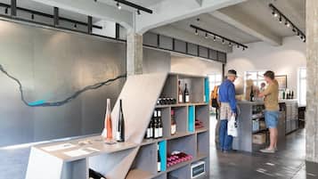 A modern interior with exposed concrete beams, a wine display, and a map on the wall.