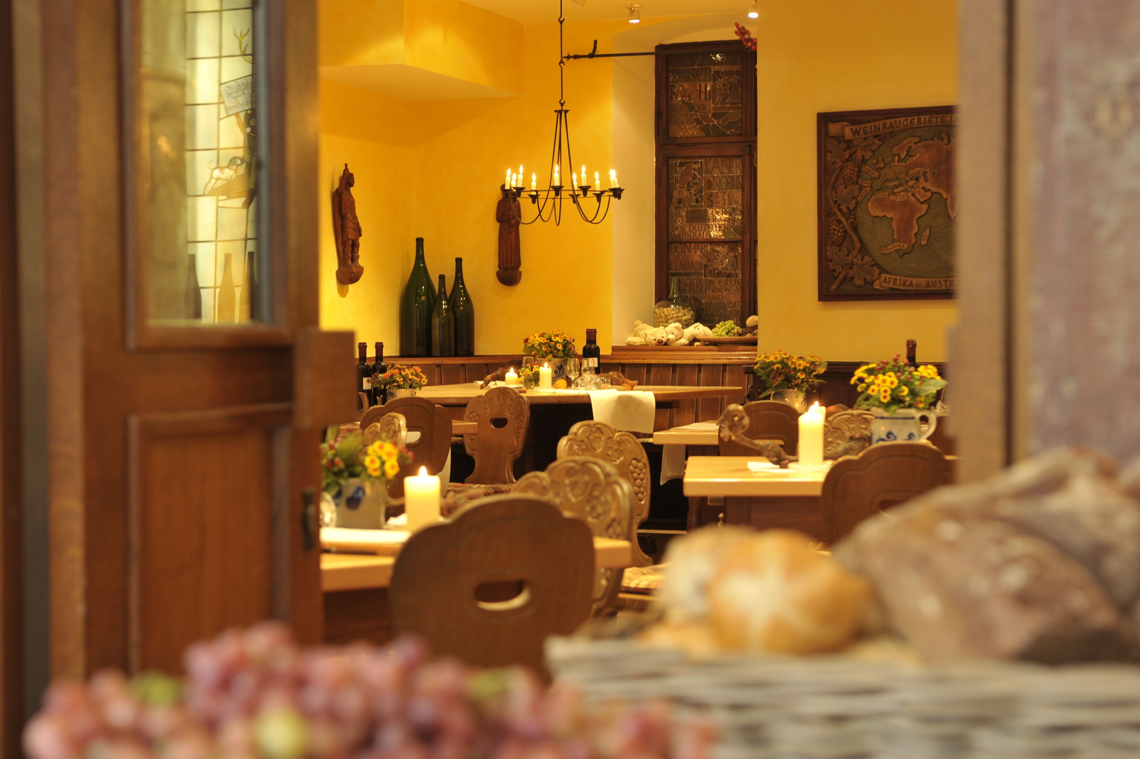 A warmly lit restaurant interior with wooden furniture, candles, and a decorative wall map.