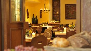 A warmly lit restaurant interior with wooden furniture, candles, and a decorative wall map.