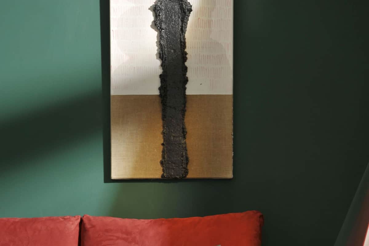 A red sofa with a glass table and metal legs in a room with a wooden floor and a green wall.