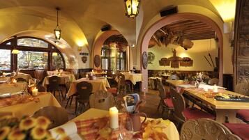 A restaurant with multiple tables set for dining, featuring candles and a warm ambiance.