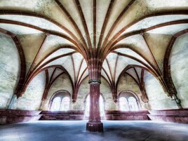 Interior de una catedral con techos abovedados altos y ventanas en arco.