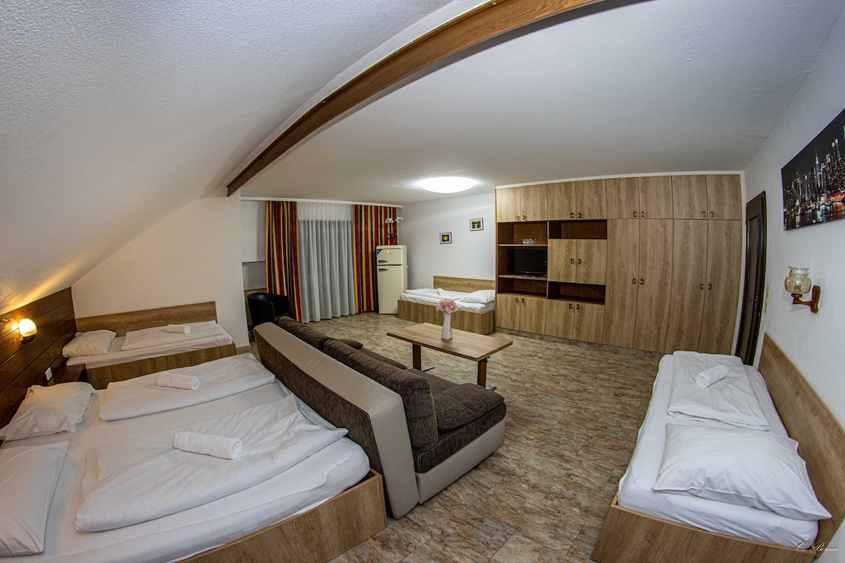 A hotel room with two beds, a sofa, a small table, and a TV.