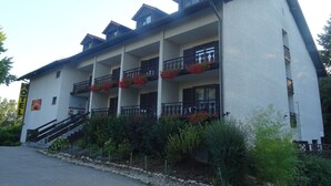 A multi-story hotel with balconies, a staircase, and a garden area. - Apparthotel Alte Innbruecke (Neuhaus am Inn)