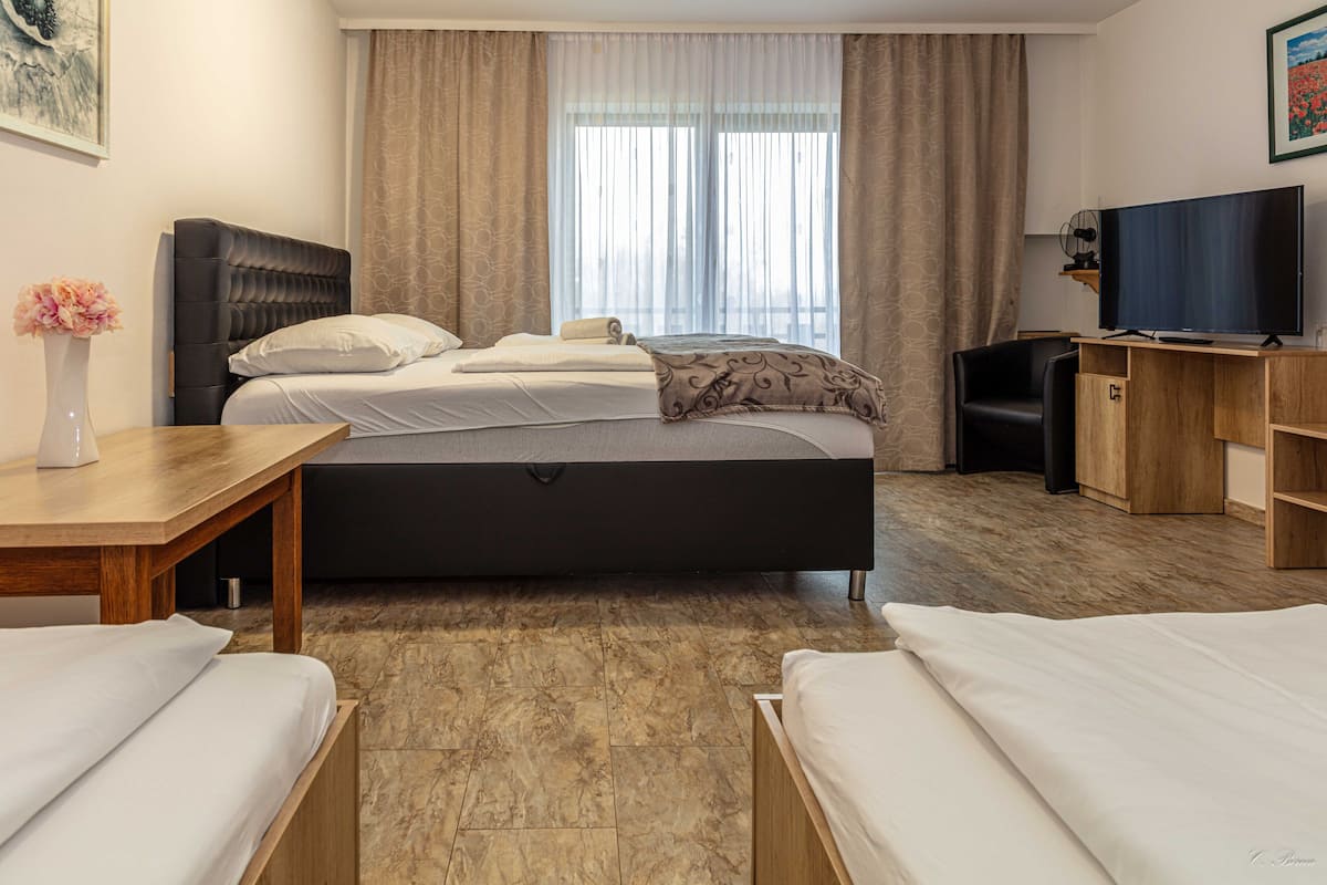A hotel room with a bed, a TV, a desk, and a chair.