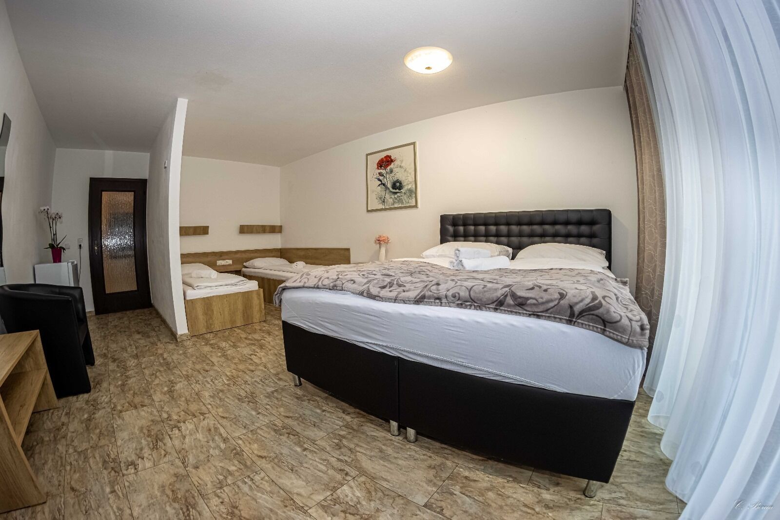 A hotel room with a large bed, a desk, and a chair.