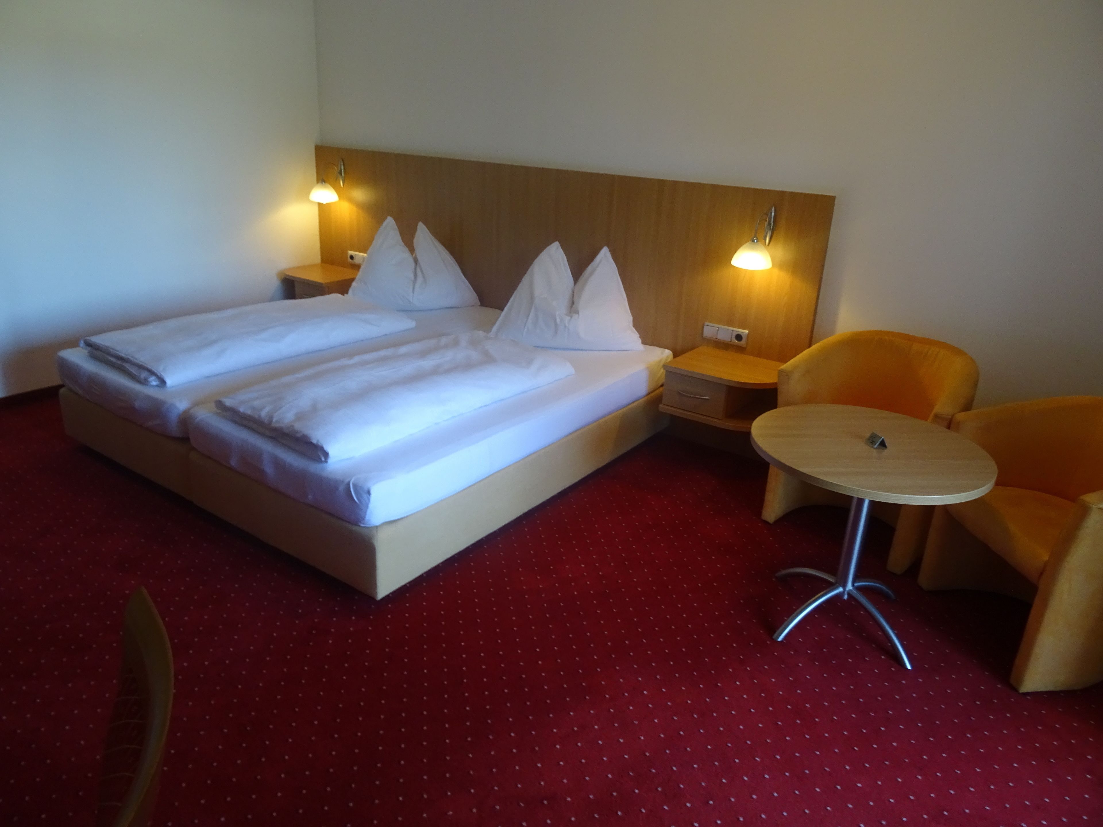 Habitación de hotel con una cama grande, dos mesitas de noche, una pequeña mesa redonda y dos sillas.