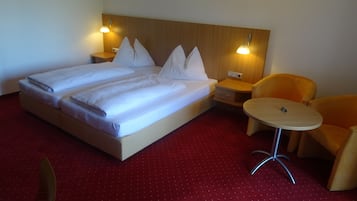 Habitación de hotel con una cama grande, dos mesitas de noche, una pequeña mesa redonda y dos sillas.