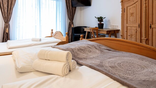 A hotel room with a bed, a desk, a chair, a television, and a wardrobe. - Apparthotel Alte Innbruecke (Neuhaus am Inn)