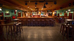 Un bar con mostrador de madera, taburetes y un cartel de 'GUINNESS'.
