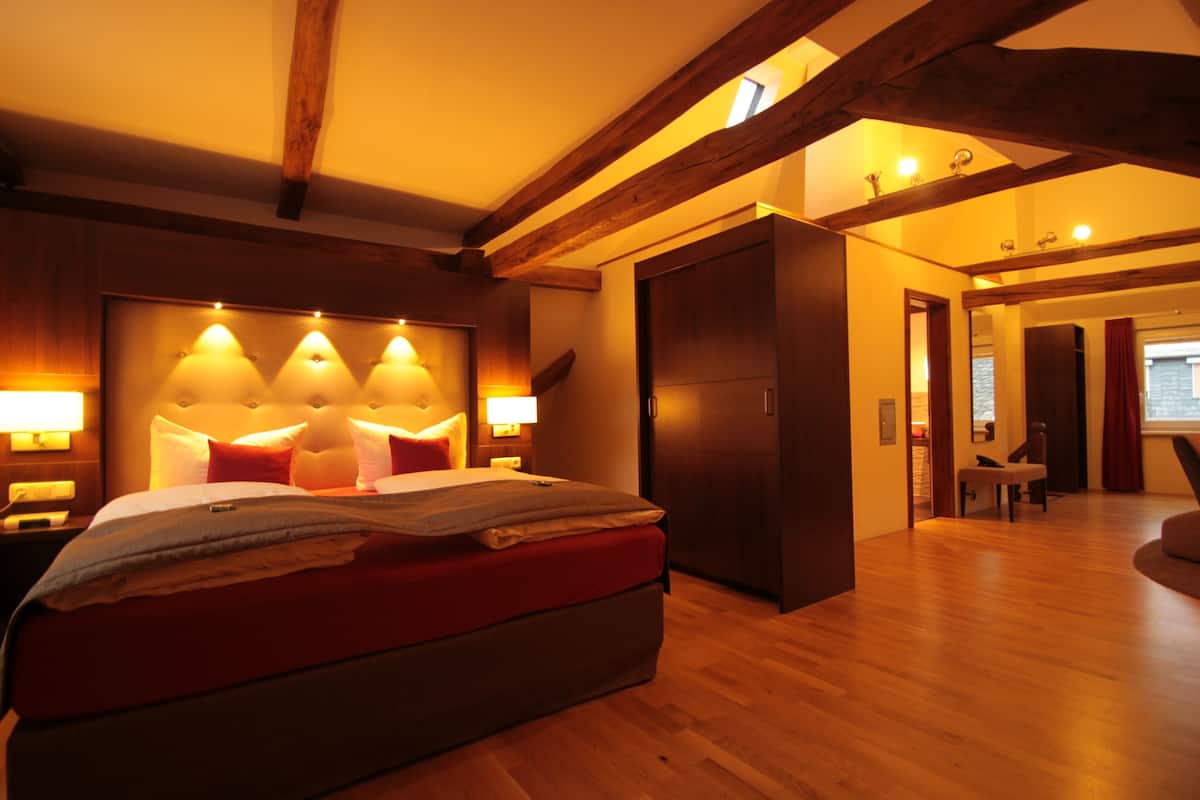 A modern bedroom with a large bed, wooden beams, and a built-in headboard with lights.