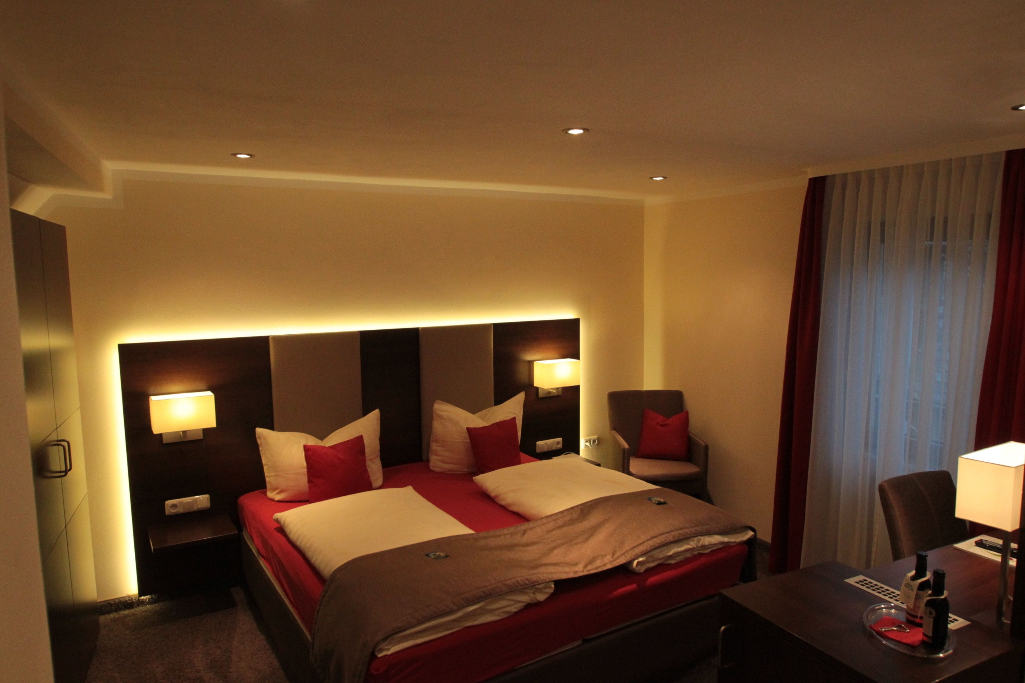 Una habitación de hotel con una cama grande, mesitas de noche, un escritorio y una silla.