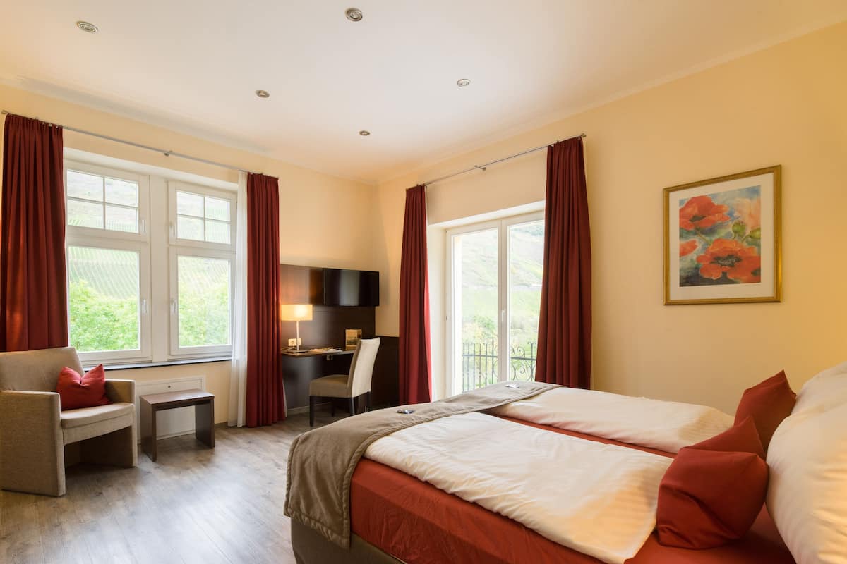 A hotel room with a bed, a desk, a chair, and a window with curtains.