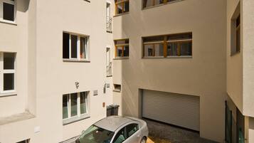 Un edificio de varios pisos con un área de estacionamiento y un coche aparcado sobre una base de madera.