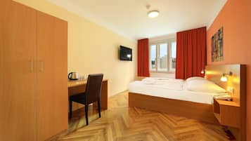Ein Schlafzimmer mit Bett, Schreibtisch, Stuhl und Fernseher an der Wand.