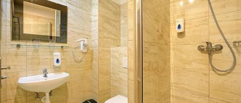 A modern bathroom with a glass-enclosed shower, a white sink, and a toilet.
