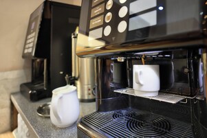 En kaffemaskine med digitalt display og en mælkeskummer.