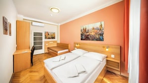 Habitación de hotel con cama, escritorio, silla, armario y un cuadro en la pared.