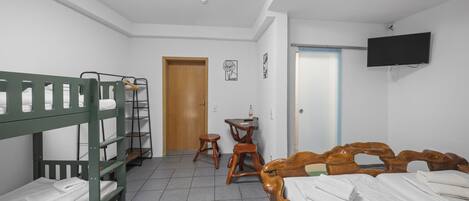Una habitación con literas, un escritorio, una silla y un televisor colocado en la pared.