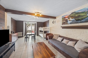 Un salon moderne comprenant un canapé, une table basse en bois, un téléviseur et un coin repas avec des chaises et une table.