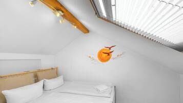 Ein Schlafzimmer mit Bett, Holz-Kopfteil, weißer Bettwäsche, Wandgemälde und einem Dachfenster.