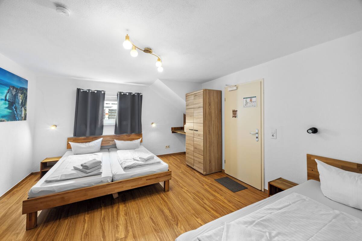 A modern hotel room with a wooden bed, a wardrobe, a desk, and a view of the sea.