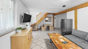 Una sala de estar moderna con una escalera de madera, un televisor de pantalla plana, un sofá y una mesa de comedor.