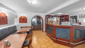 Un restaurante con barra, mesas y una cocina visible a través de un arco.