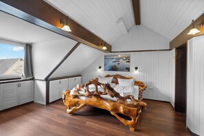 A bedroom with a sloped ceiling, a wooden bed frame, a painting on the wall, and a window with curtains. - Gaestehaus Parkblick (Rust)