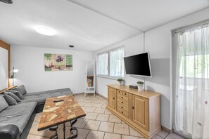 Un salon moderne comprenant un canapé, une table basse, un téléviseur et un meuble.