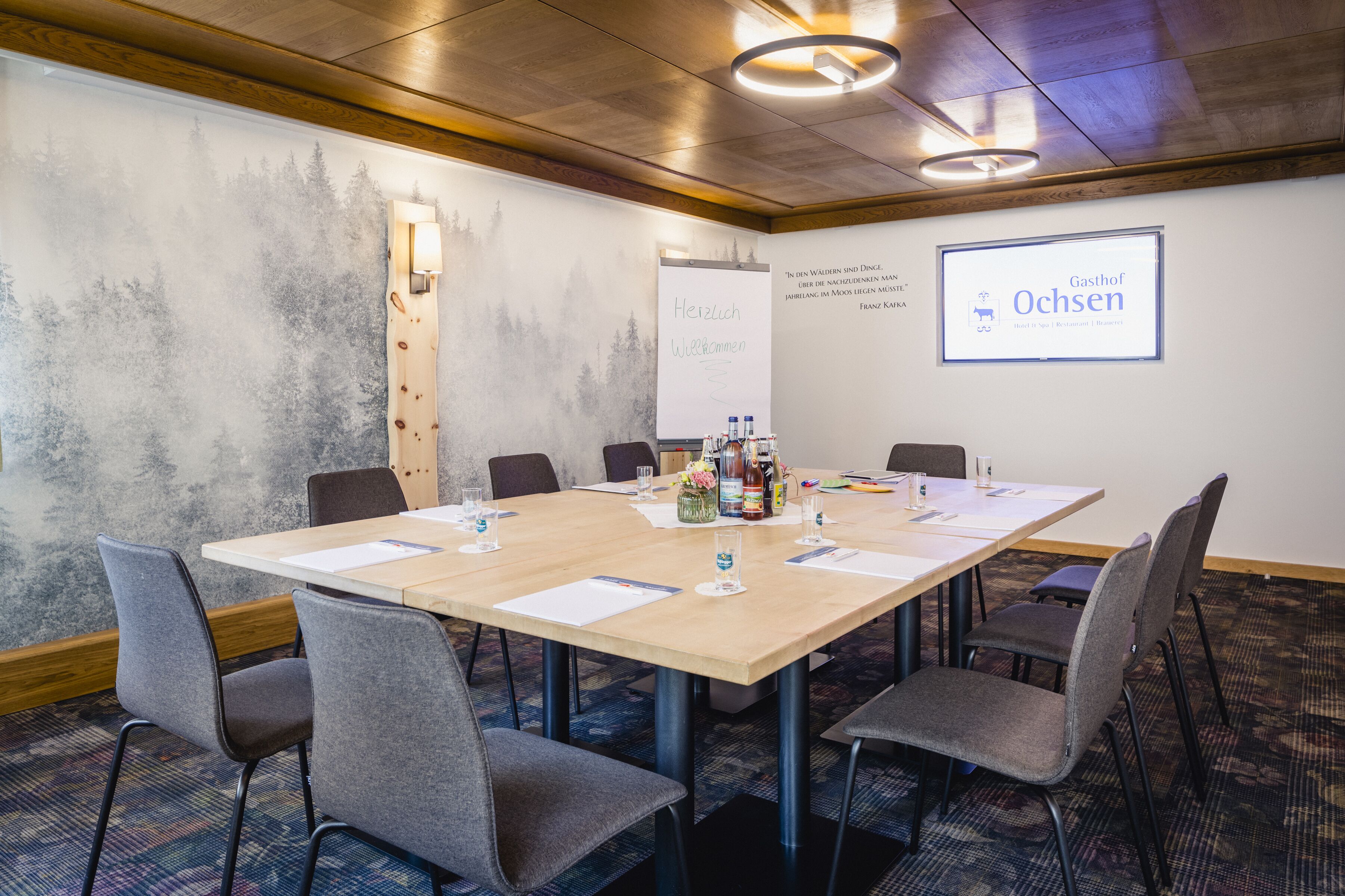 A conference room with a long table, six chairs, and a projector screen displaying "Gasthof Ochsen".