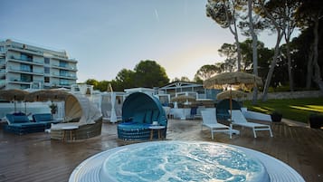 Een dakzwembad met ligbedden, een whirlpool en parasols.