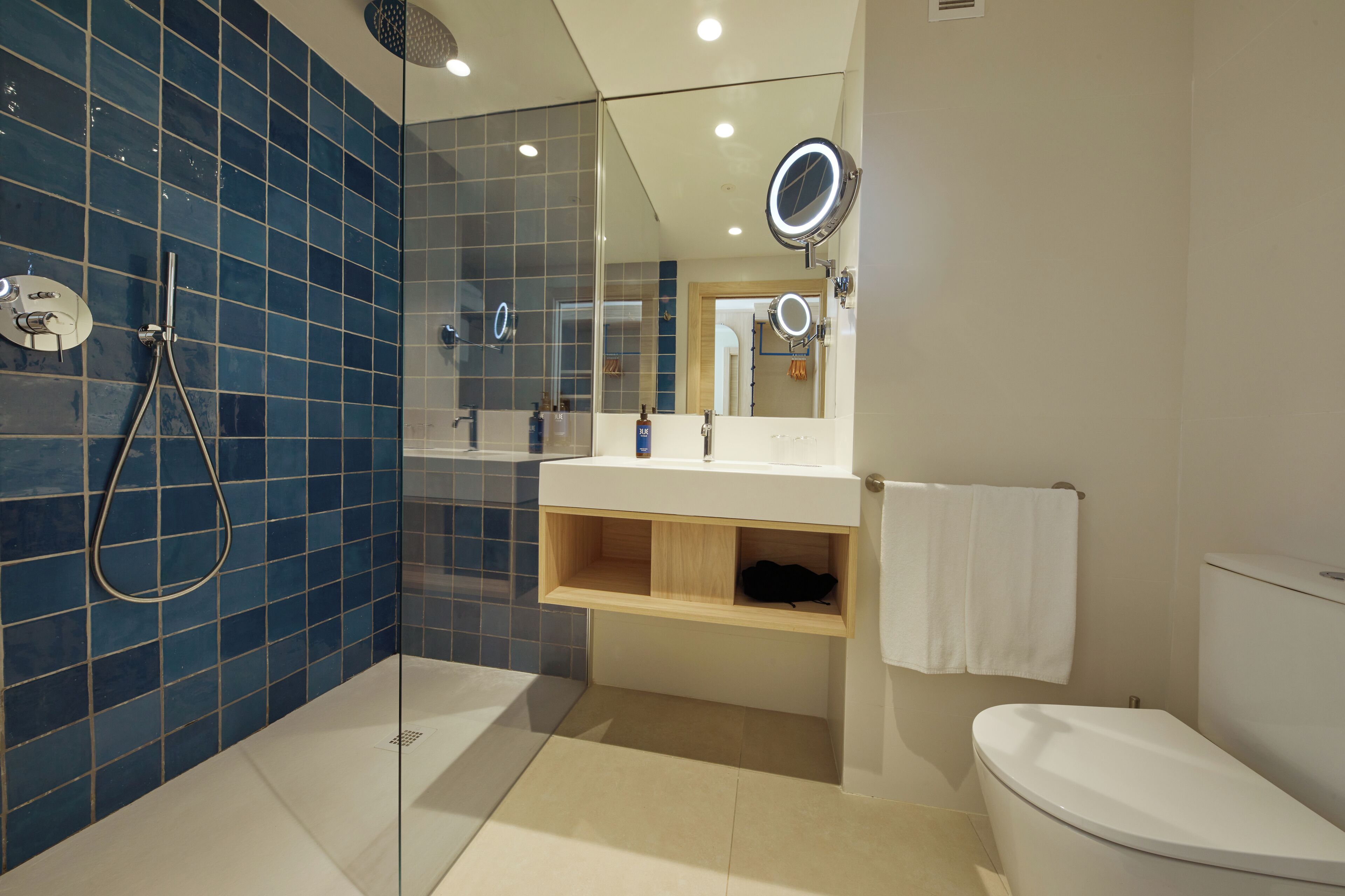 A modern bathroom with a glass-enclosed shower, a white toilet, and a vanity with a mirror.