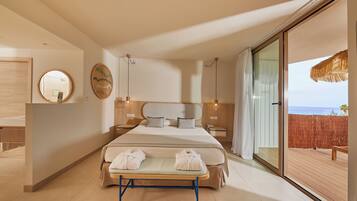 A modern hotel room with a large bed, a bedside table, a mirror, and a view of the sea through a sliding glass door.
