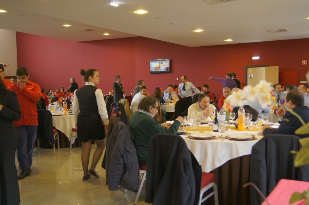 A conference room with round tables, attendees seated, and a television mounted on the wall.