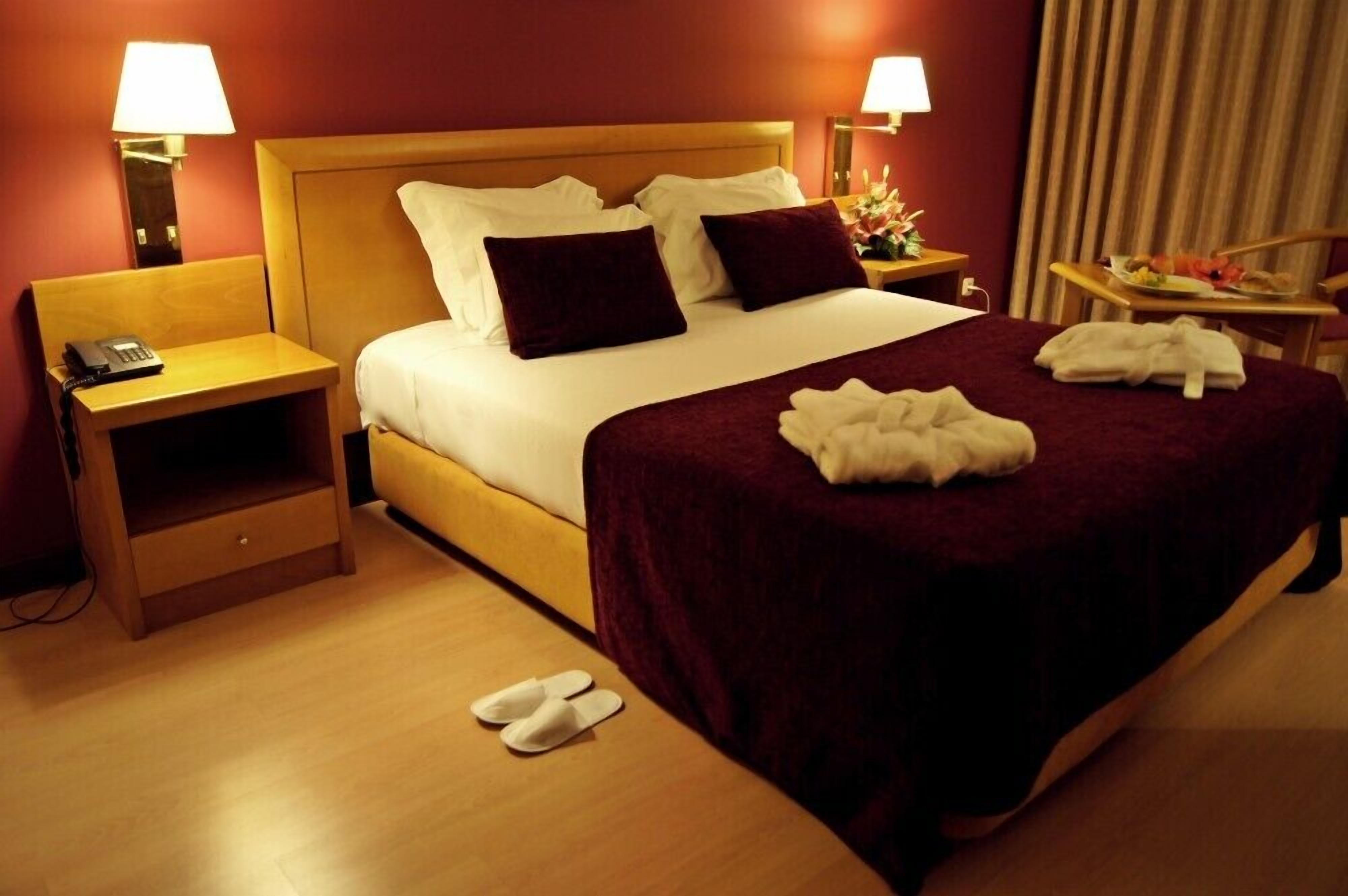 Een hotelkamer met een groot bed, twee nachtkastjes en een stoel.