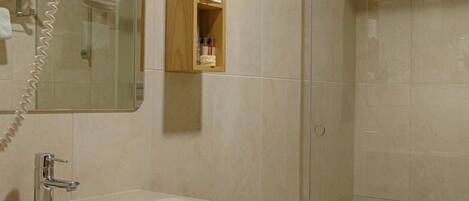 Un baño con lavamanos, espejo y cabina de ducha de vidrio.