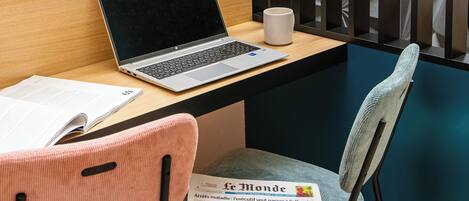 Un espacio de trabajo con una computadora portátil, una taza, y una silla con un periódico.